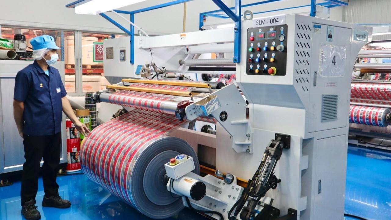 Operator monitoring flexible packaging film on a lamination machine